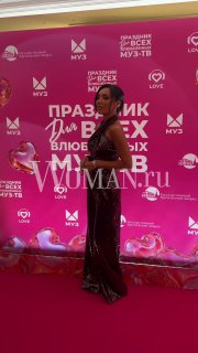 Женщина в вечернем платье идёт по красной дорожке перед брендволлом с логотипами концерта «Праздник для всех влюблённых МУЗ‑ТВ».