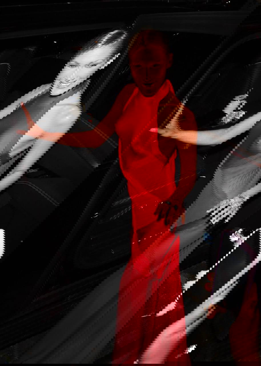 Белла Хадид выходит из автомобиля в красном прозрачном платье Schiaparelli — кадр папарацци демонстрирует силуэт и детали кроя.