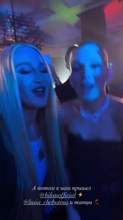 Селфи Люси Чеботиной с гостьей на танцполе в наушниках; разноцветное освещение и улыбающиеся лица создают атмосферу вечеринки и веселья.