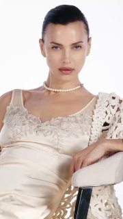 Студийный портрет модели в бежевом шелковом платье и жемчужном ожерелье на светлом фоне — кадр из рекламной кампании модного бренда.