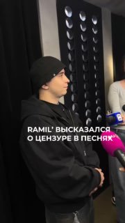Ramil’ в профиль на сольном концерте: артист в чёрной шапке и худи стоит рядом с микрофоном и журналистами, репортажный кадр.