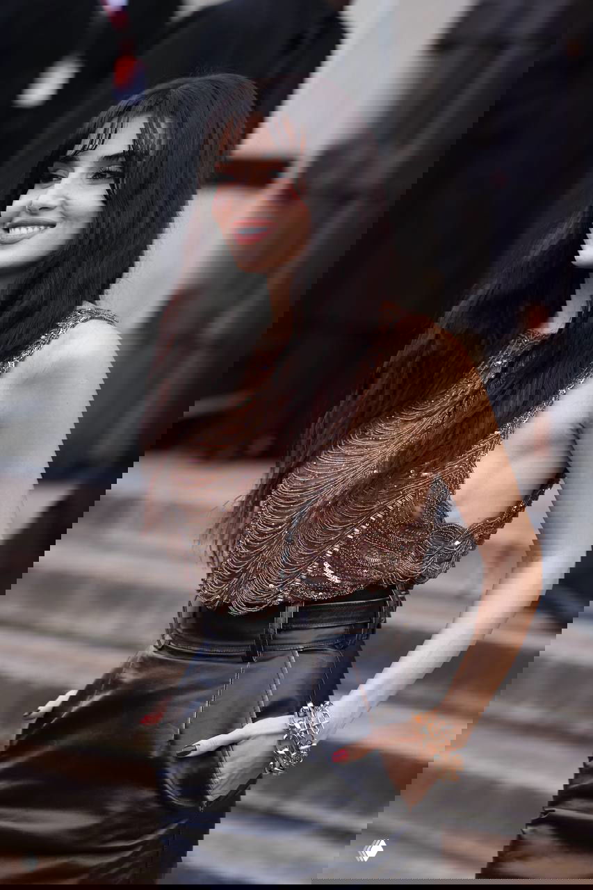 Боковой портрет на лестнице показа Elie Saab в Москве: Ханде Эрчел улыбается в коричневом топе и кожаной юбке, видны браслет, маникюр и детали образа.