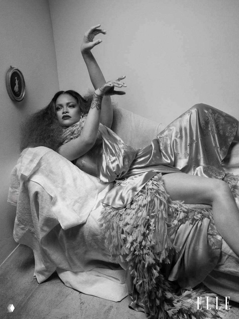 Рианна в элегантном платье на софе: чёрно-белая фотография с театральной позой, драпировки ткани и ретро‑атмосфера модной съёмки.