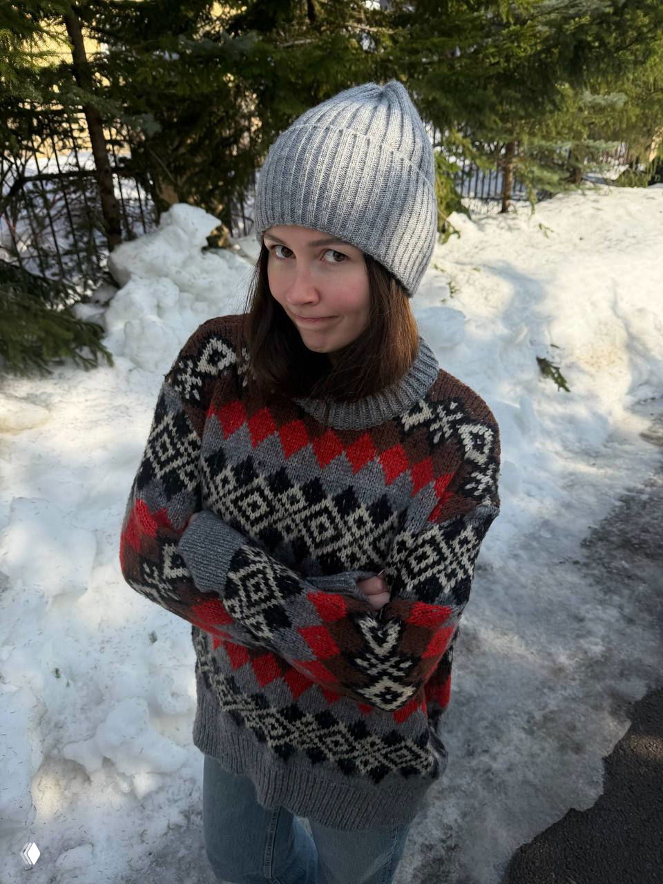 Портрет дочери Анастасии Заворотнюк в серой шапке и теплой вязаной кофте на фоне снега и елей во время прогулки в Москве.