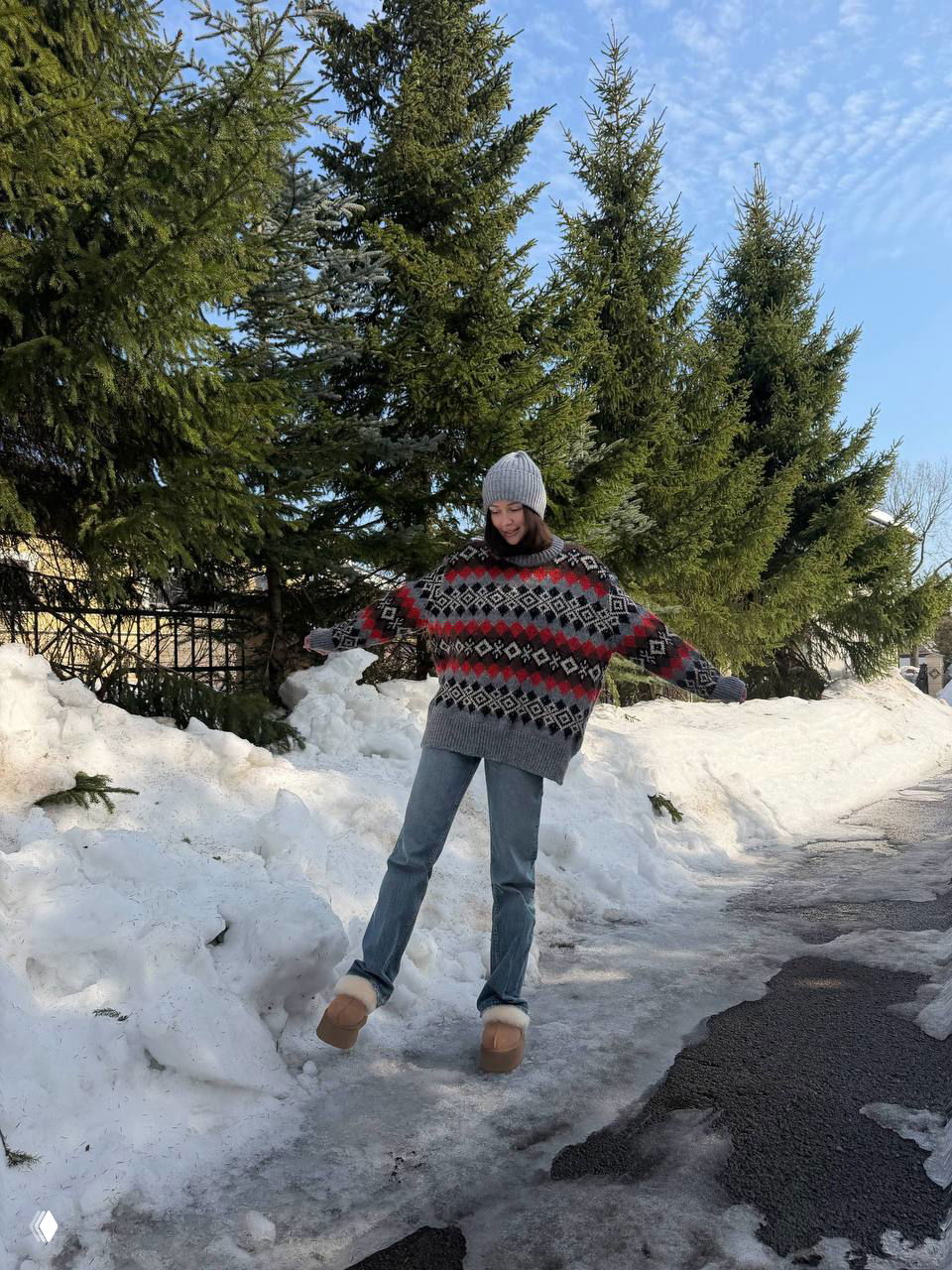 Дочь Заворотнюк в полный рост в свитере и джинсах на фоне сугробов и хвойных деревьев — зимняя уличная сцена в московском районе.