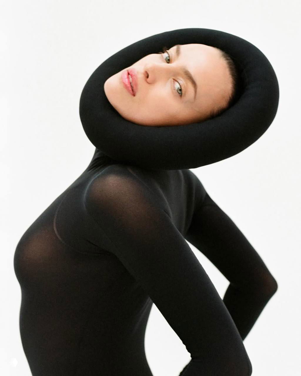 Ирина Шейк в чёрном облегающем костюме и необычном круглой подушке вокруг головы — концептуальный кадр из съёмки.