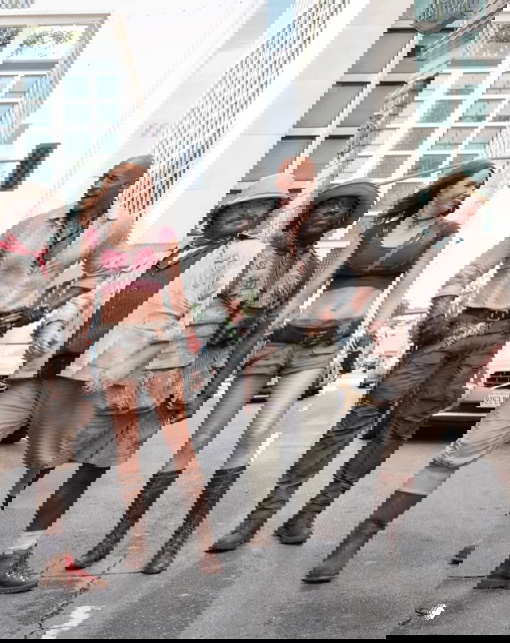 Кадр со съёмочной площадки фильма: Дуэйн Джонсон в образе персонажа идёт по городской улице рядом с коллегами-актёрами; видна кинодекорация и костюмы.