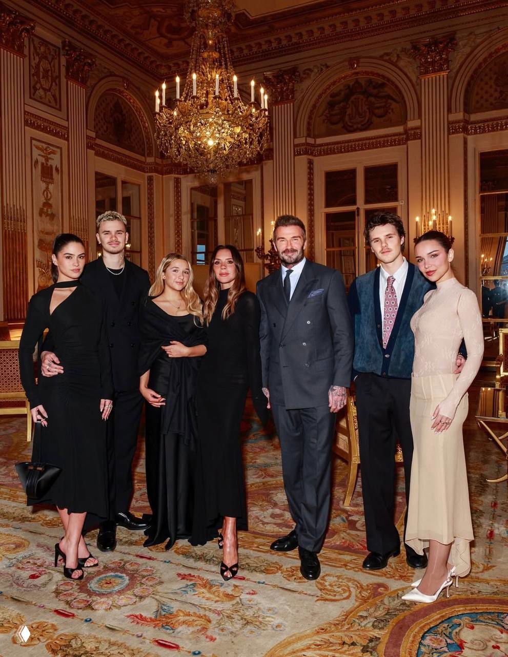 Постановочная групповая фотография: несколько человек в вечерних нарядах позируют в роскошном зале во время парижского модного вечера.