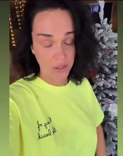 Крупный план певицы Славы в яркой футболке на фоне украшенной ёлки — превью видеообращения, связанного с квартирным скандалом и судебным спором.