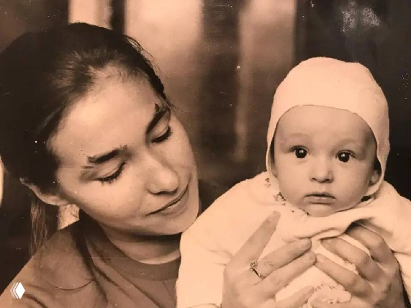 Чёрно‑белая архивная фотография: молодая женщина держит на руках младенца, нежный семейный снимок из детства певца.
