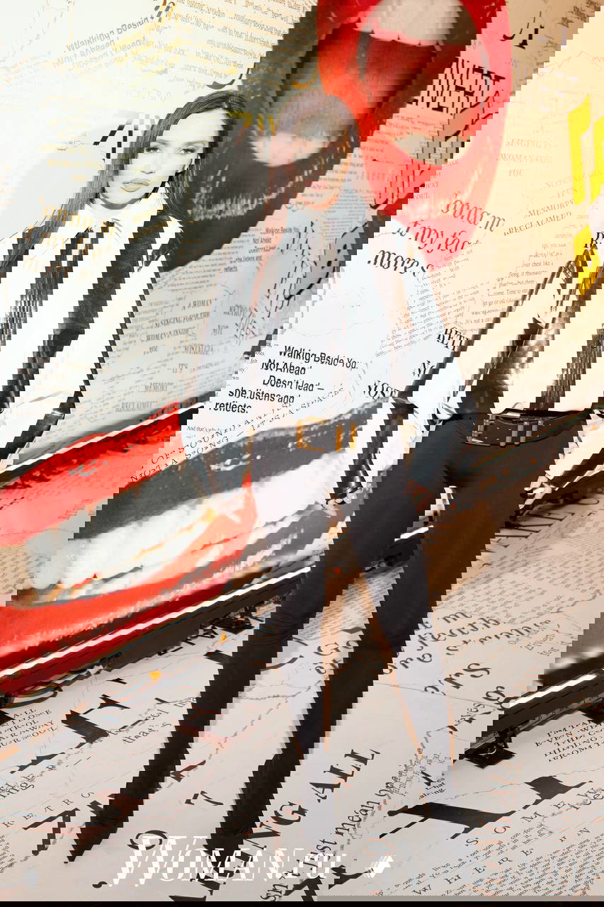 Женщина в черно‑белой блузе и узких штанах стоит у яркой фотостены с надписями и крупным красным изображением губ шоу Zivert