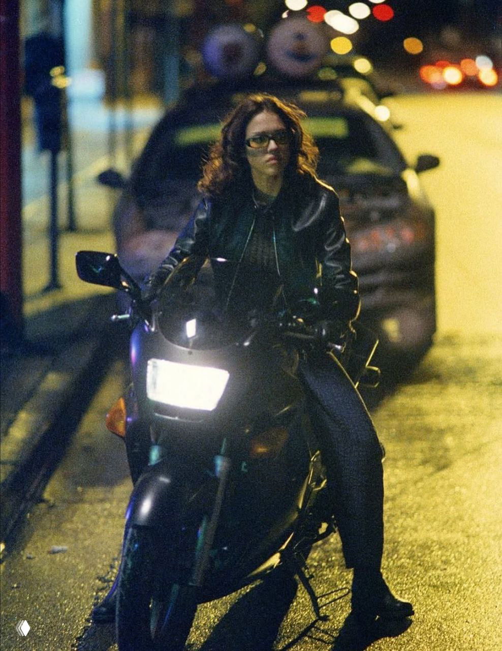 Джессика Альба едет на мотоцикле по городской улице ночью; кадр носит характерный для сериала 2000-х кинематографический вид.