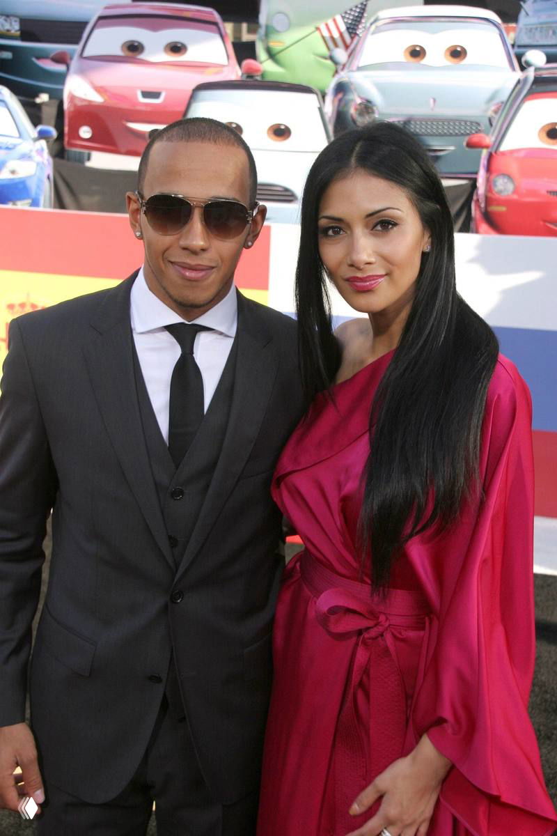 Пара на красной ковровой дорожке: мужчина в костюме и женщина в ярком платье позируют для фотографов; кадр по пояс, формальная фотосессия.