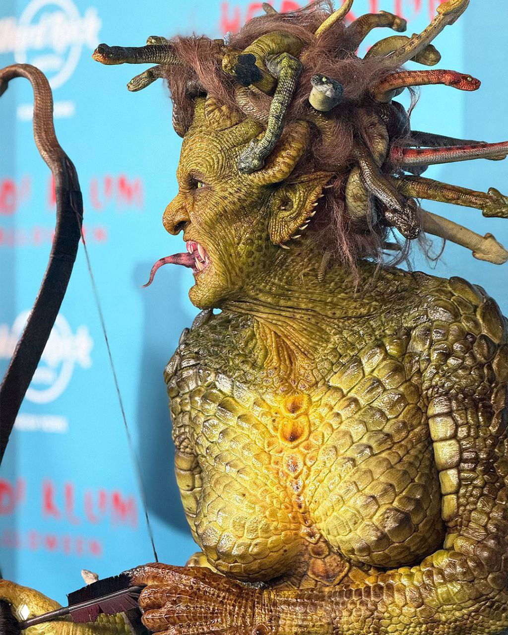 Профильный кадр Хайди Клум в гриме Медузы: роботизированные змеи в причёске, детализированные чешуйки на шее и выражение лица актрисы.