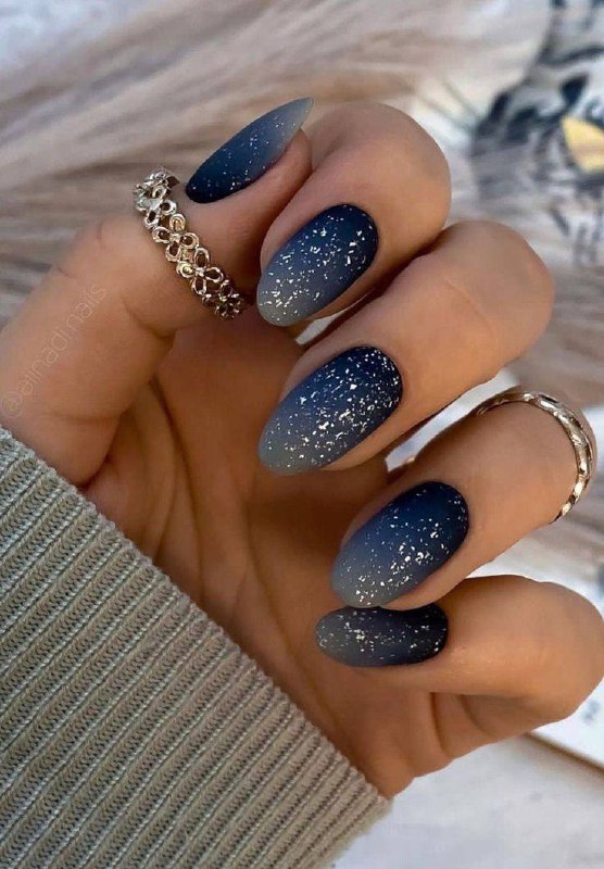 Градиентный синий матовый маникюр с белыми «снежными» брызгами и овалом формы ногтей, подходит к холодным праздничным образам 2026 года.