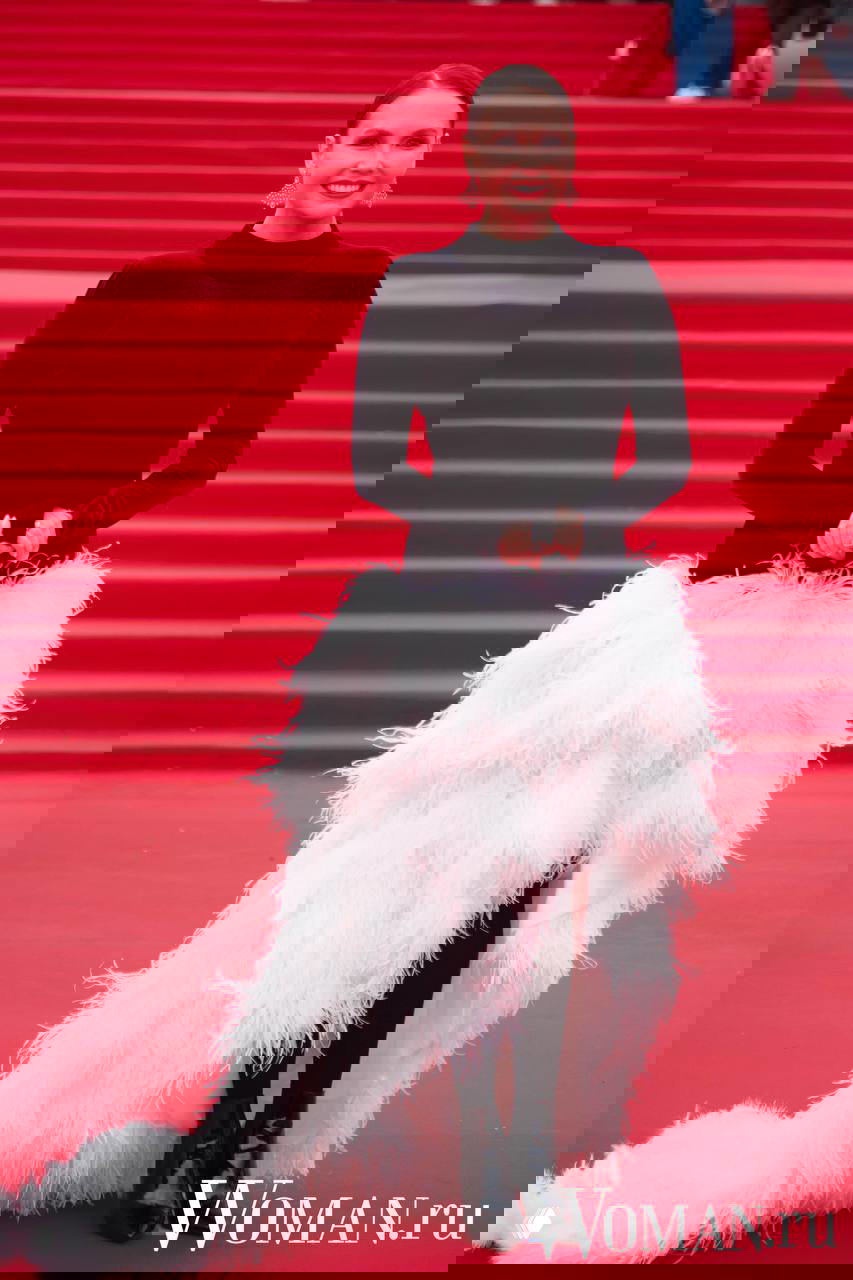 Женщина в контрастном образе — бархатный верх и пышный перьевый низ — позирует на красной дорожке Московского кинофестиваля, яркий текстурный эффект.