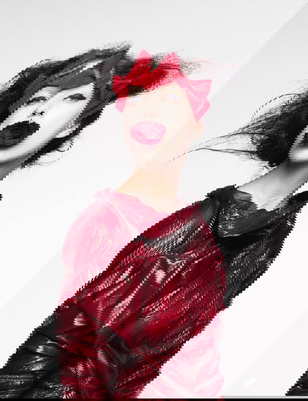 Портрет Ирины Шейк в красочном образе: яркий красный головной аксессуар и роза во рту, контрастный макияж и студийный свет подчёркивают художественный стиль съемки.