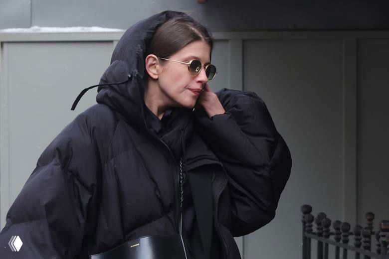 Анна, дочь Ольги Чиповской, в чёрной одежде и солнцезащитных очках выходит или находится у здания театра во время церемонии прощания.