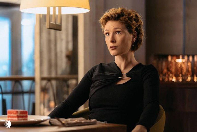 Артефактный крупный план актрисы в интерьере: кадр повреждён цифровыми шумами, заметны элементы декора и реквизит.