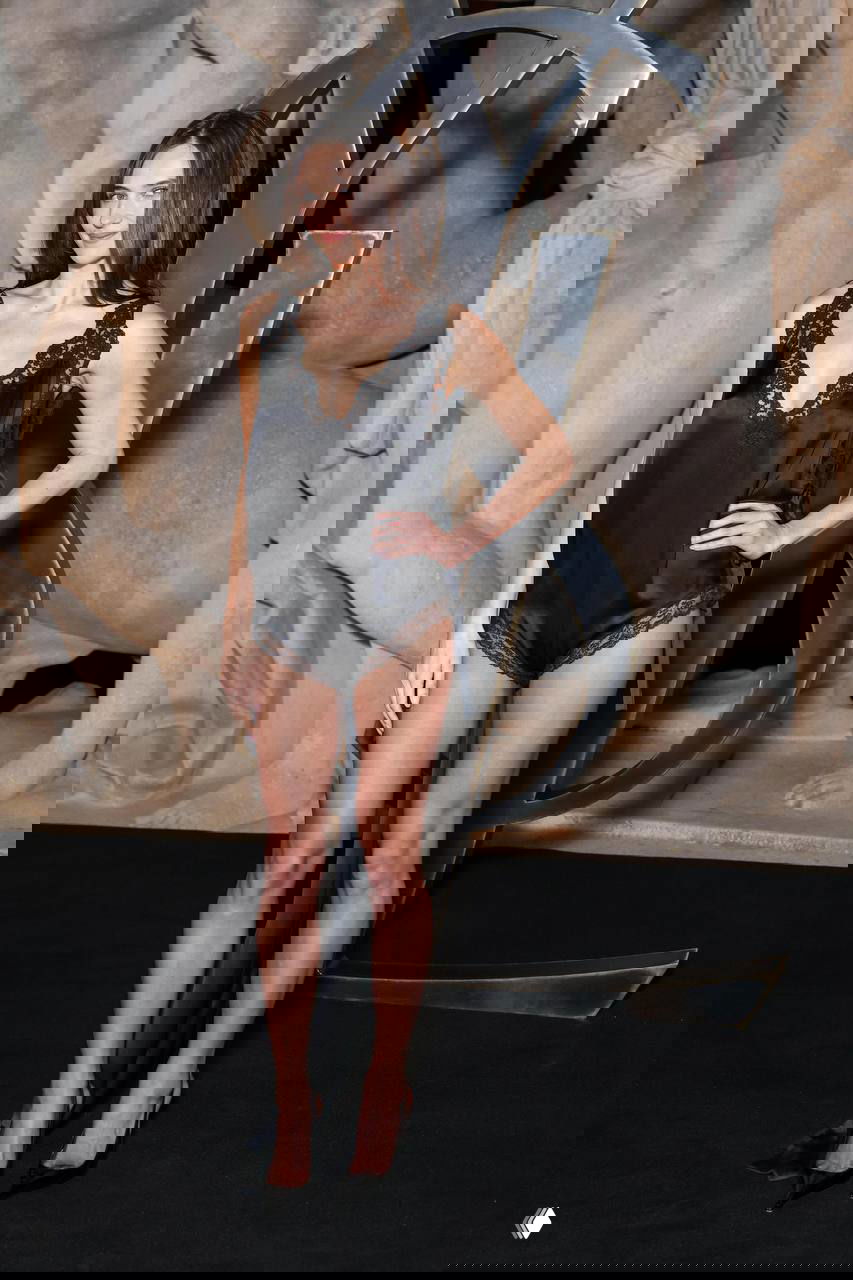 Модель в чёрной кружевной комбинации и туфлях на шпильке на фоне больших декоративных букв YSL во время показа коллекции Saint Laurent в Париже.