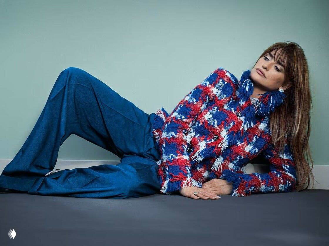 Релаксированный кадр в студии: женщина в текстурном жакете и широких брюках лежит в задумчивой позе — стилизованная съёмка для журналов моды.