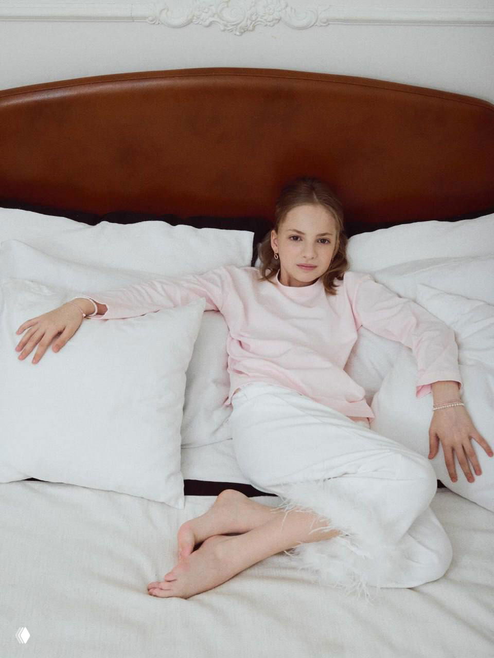 Подросток расслабленно лежит на кровати в светлой комнате: эстетичный интерьер, спокойная поза в домашней обстановке.