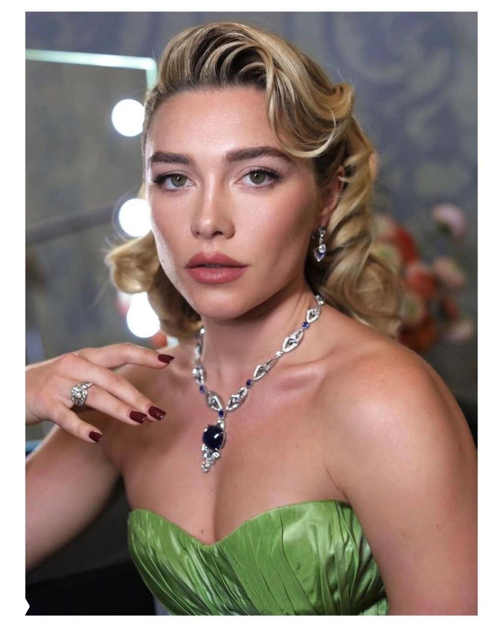 Крупный план женщины в зелёном корсете и дорогом ожерелье: вечерний макияж, прическа и украшения на светском мероприятии.