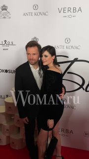 Пара в вечерней одежде позирует на фоне бренд-волла OK! Awards; кадр подчёркивает наряды гостей и атмосферу мероприятия.