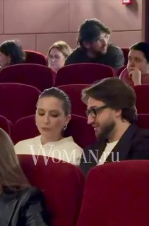 Пара в креслах зрительного зала во время показа: женщина и мужчина общаются, вокруг другие зрители, фокус на их беседе.