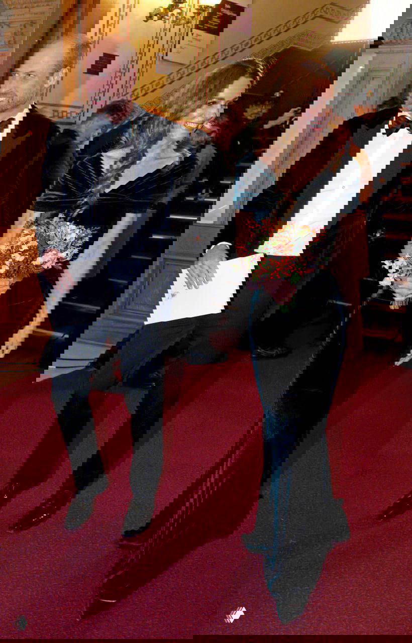 Принц Уильям и принцесса Кэтрин покидают мероприятие; Кэтрин держит букет и улыбается, кадр сделан при выходе из зала.