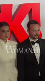 Мужчина и женщина в официальных нарядах на фоне крупного красного логотипа OK!; кадр с красной дорожки и водяным знаком WOMAN.ru.