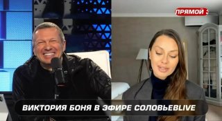 Два человека в телеэфире: мужчина улыбается в студии, женщина отвечает по видеосвязи; внизу виден титр с именем.