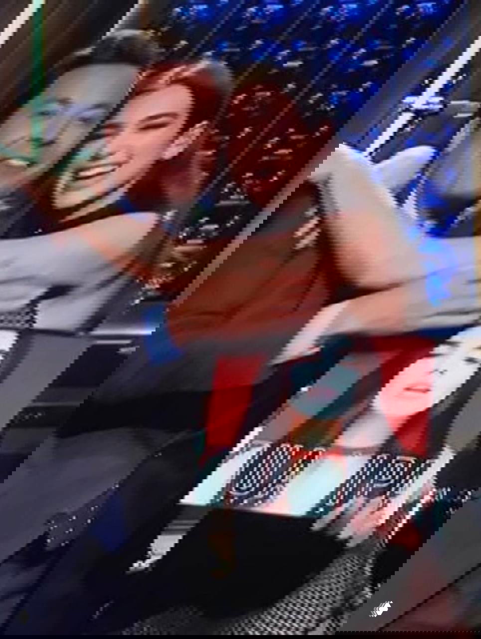 Публичные личности обнимаются на сцене шоу в архивном кадре — размытый фон, радостные улыбки и атмосфера ночного эфира.