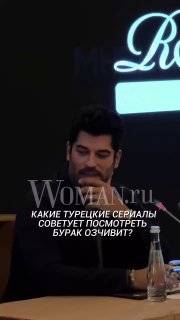 Крупный план Бурака Озчивита на пресс‑конференции в Москве: актёр сидит за столом с микрофоном и бутылкой воды, на заднем плане тёмный фон и логотип.