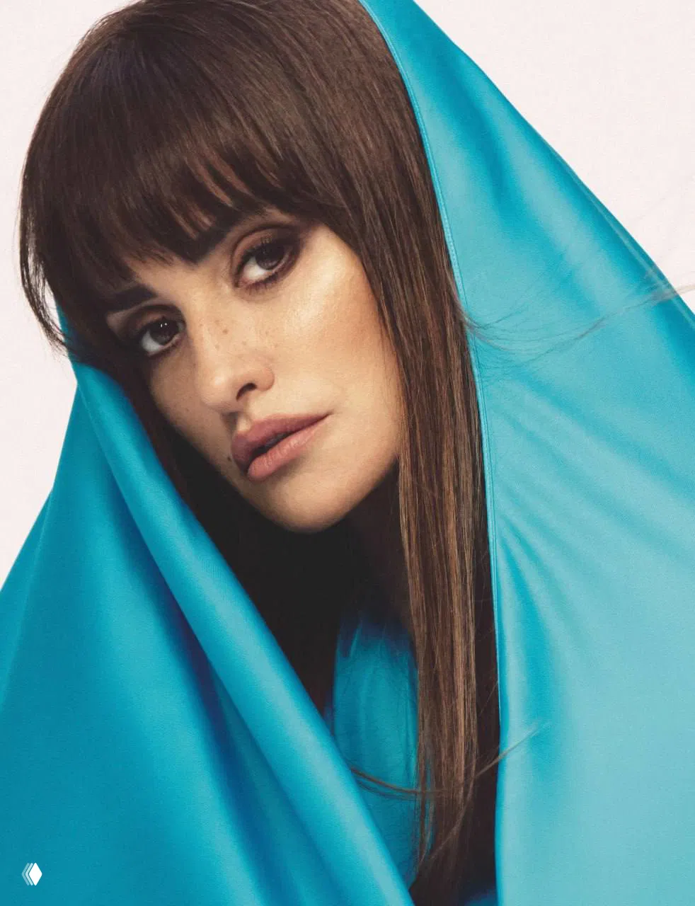 Цветной крупный план: женщина, завернутая в яркую бирюзовую ткань, мягкий свет подчёркивает текстуру ткани и черты лица.