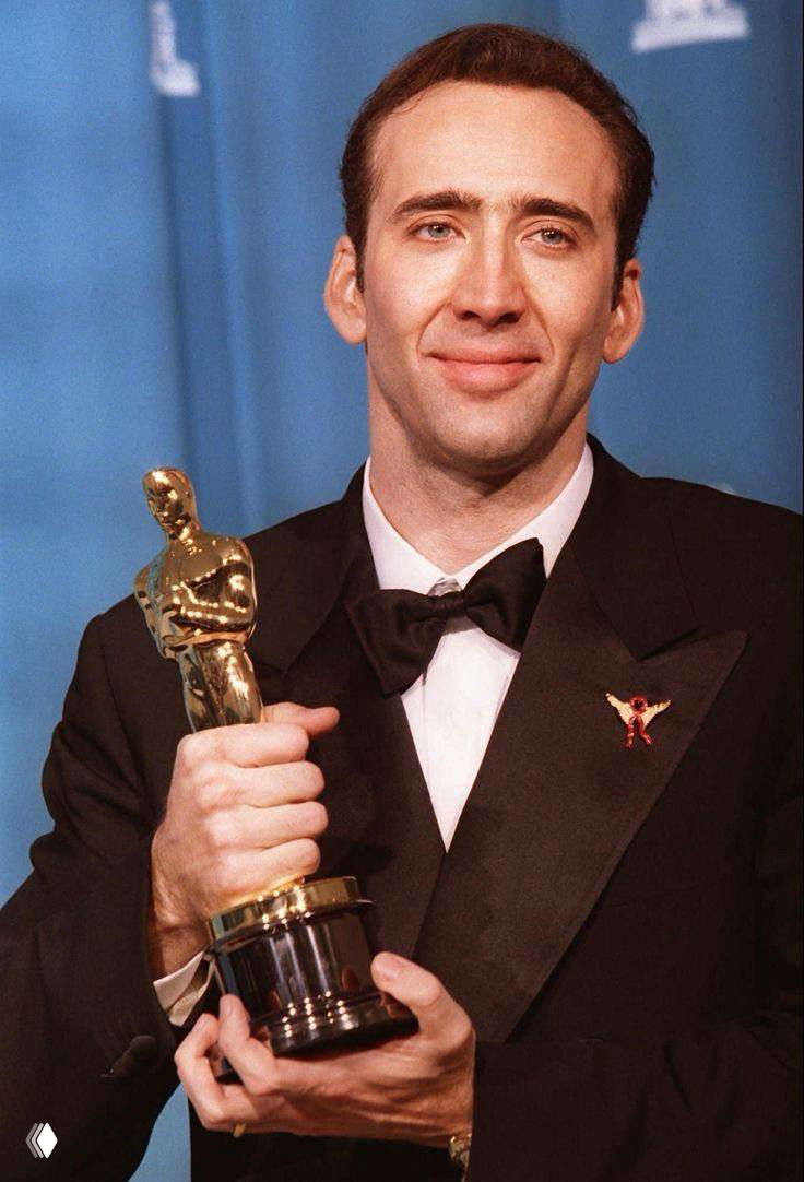 Портрет в смокинге: мужчина держит золотую статуэтку награды, официальный образ победителя кинопремии на церемонии.