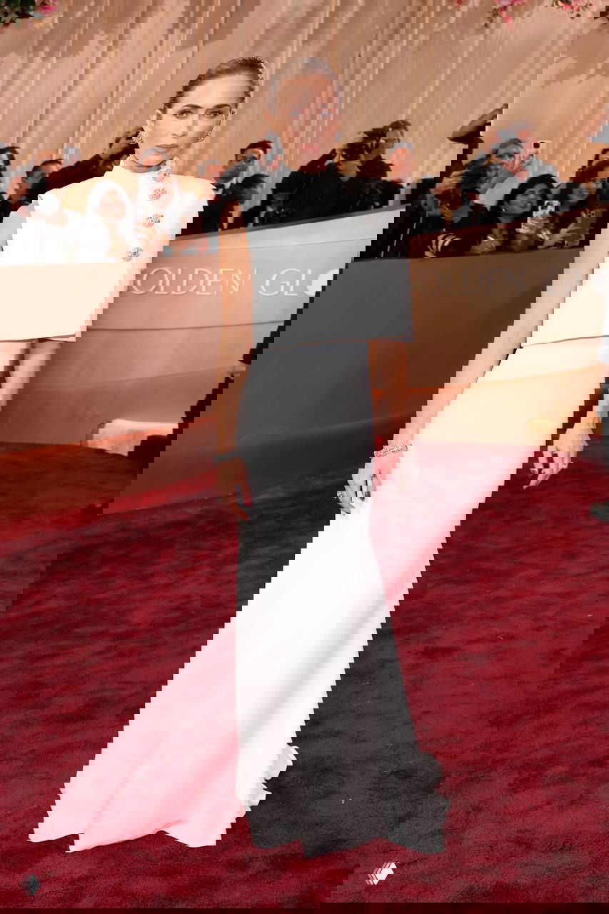 Фигура женщины в белом облегающем платье на красном ковре «Golden Globes», позирует перед фотоколлом и камерами прессы