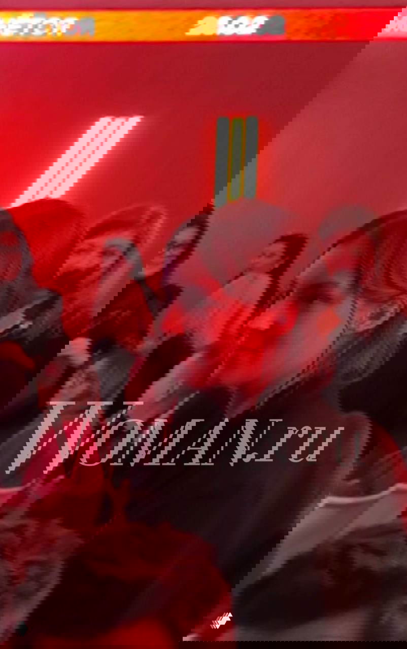 Гости премьеры в красном свете зала: крупный профиль женщины на фоне зрительного зала и логотипа, фотография с водяным знаком из репортажа