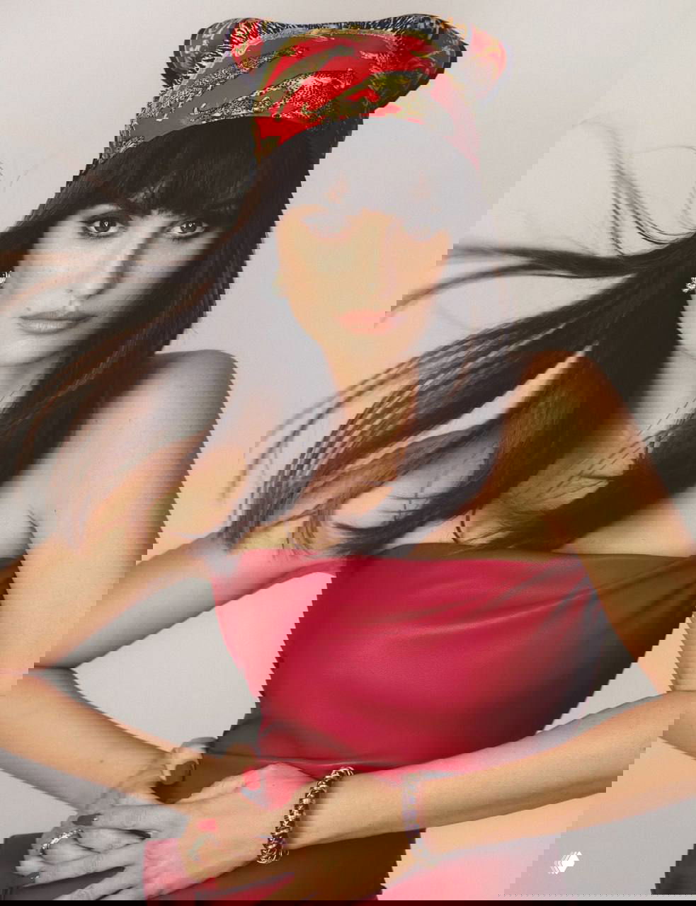 Студийный портрет женщины в красном платке и платье, волосы развеваются, свет подчёркивает контуры лица и макияж.