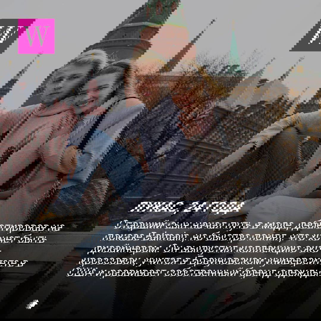 Молодой мужчина и женщина сидят на каменных ступенях у памятника в центре города; повседневная уличная сцена в прохладный день.