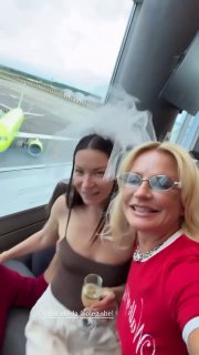 Ида и подруга с бокалами в салоне самолёта на фоне борта и окна, праздничное настроение перед прибытие в Северную Осетию