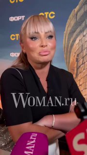 Крупный план Даны Борисовой во время общения с журналистами: видны микрофоны и фон премьеры, выражение лица серьёзное.