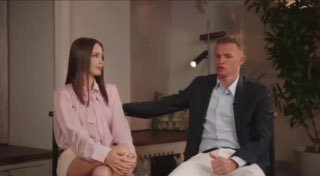 Мужчина в пиджаке и молодая девушка в светлой блузке сидят рядом в студии во время интервью; кадр передаёт семейный контекст и беседу.
