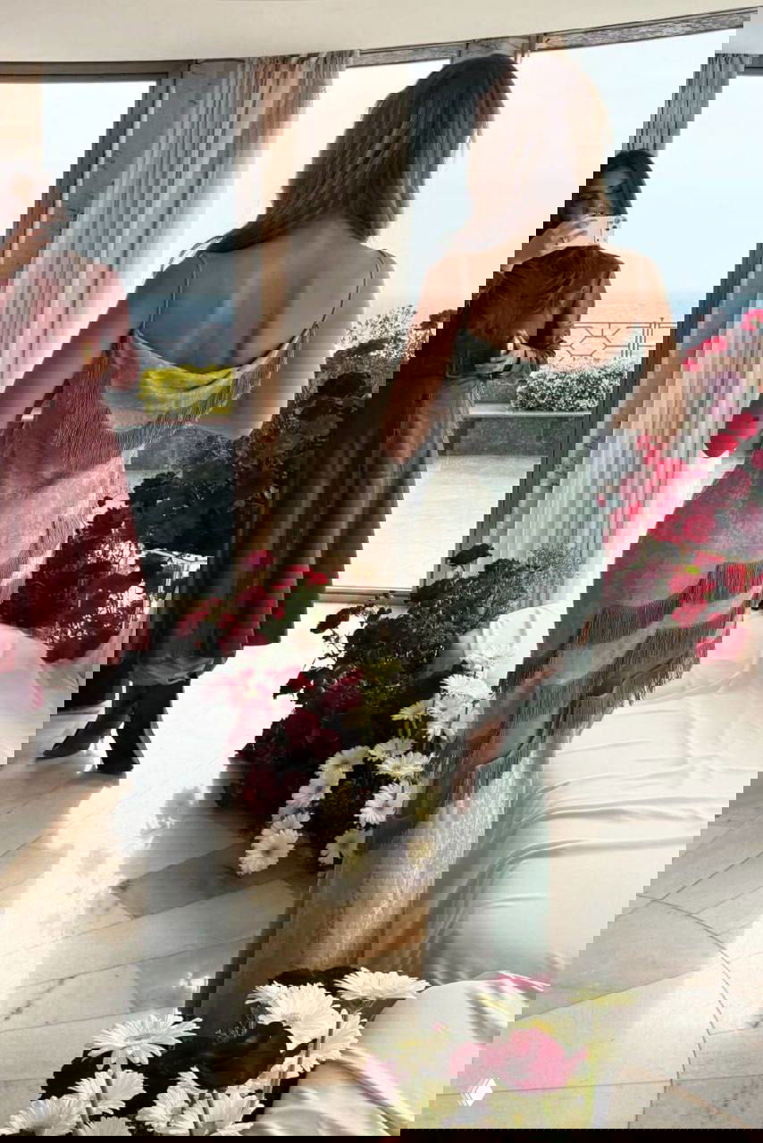 Вид сзади: Белла Хадид в драпированном винтажном платье Christian Dior с бахромой, интерьер терассы и цветы вокруг — промо Ôrəbella.