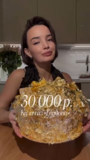 Девушка демонстрирует крупный пасхальный кулич, покрытый сусальным золотом; на фото видна подпись с ценой 30 000 ₽.