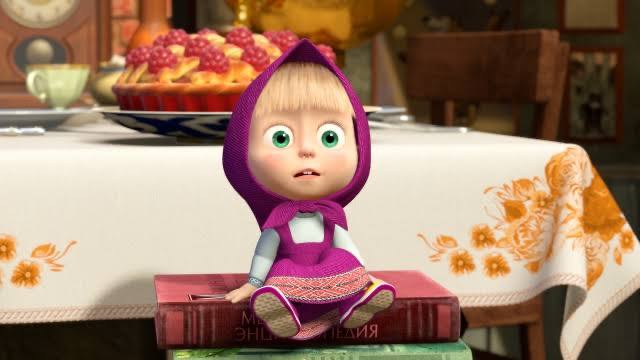 Маша в фиолетовом платочке сидит у стола, на заднем плане праздничная сервировка и пирог; на лице у Маши — удивление