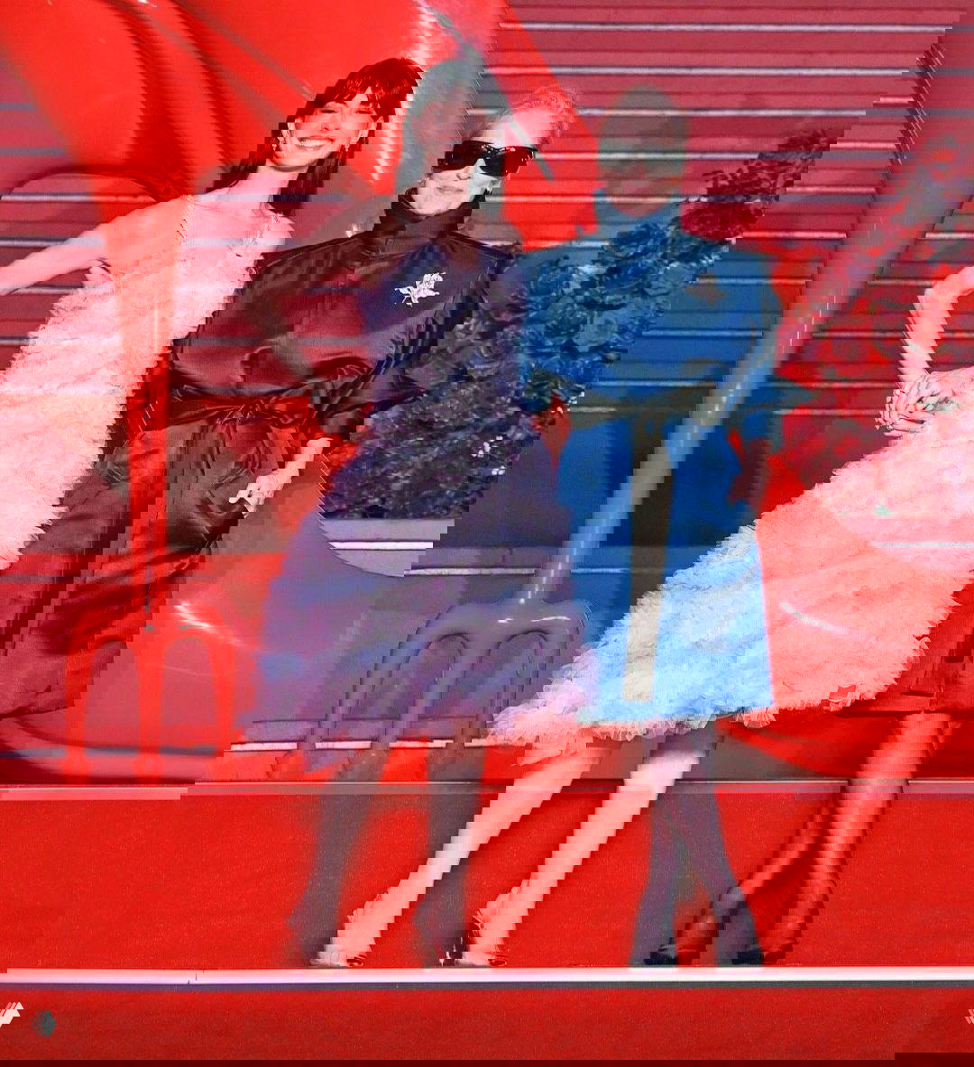 Мерил Стрип и Энн Хэтэуэй позируют на красной лестнице в Шанхае; Энн улыбается в нежном платье, Мерил в тёмно-синем образе и солнцезащитных очках.