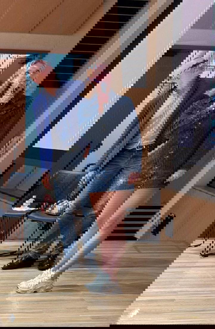 Пара стоит на сцене в аудитории: женщина держит микрофон, мужчина смотрит в зал; момент выступления на показе фильма в Японии.