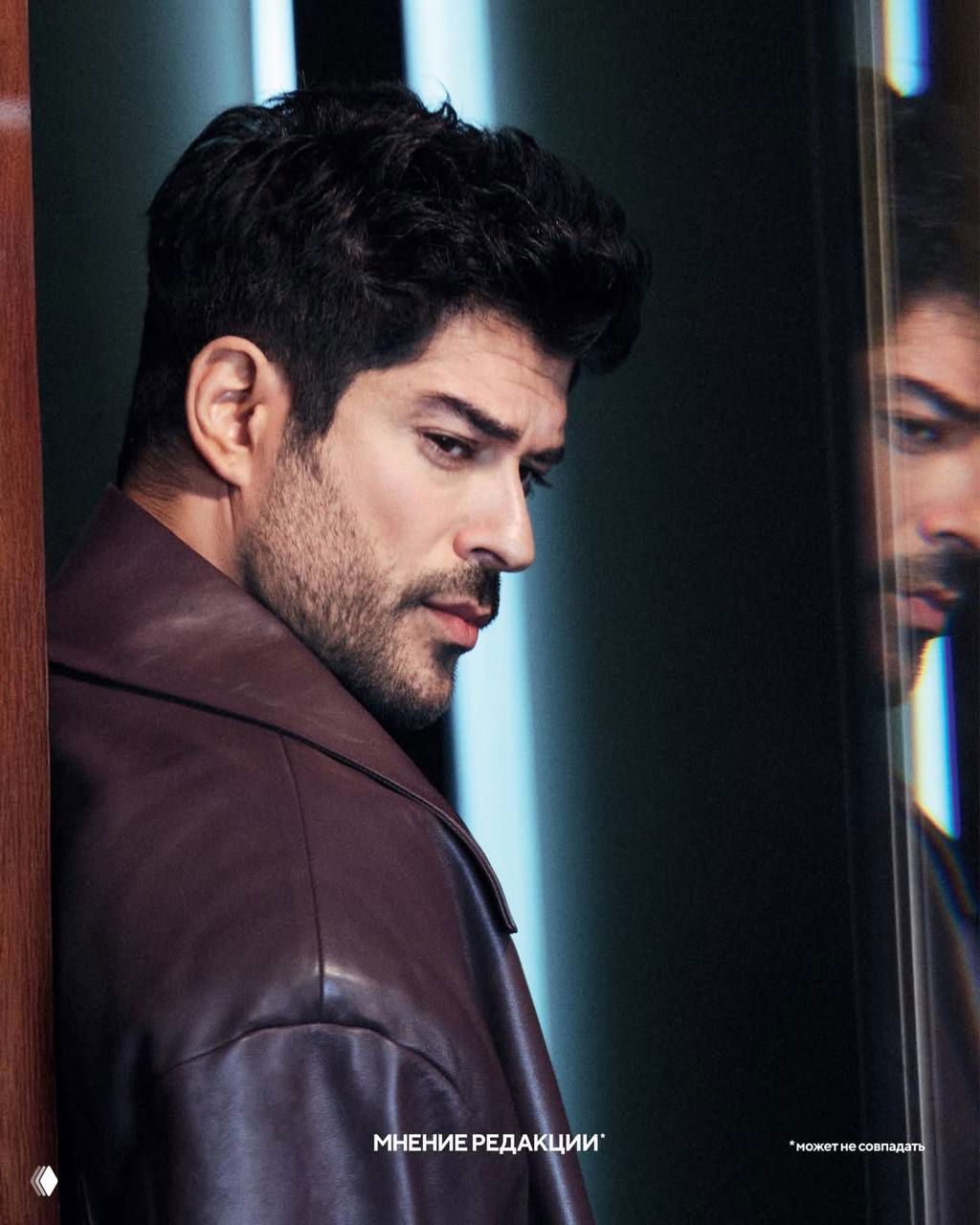 Боком снятый портрет мужчины у стеклянной поверхности: студийный кадр в кожаном пиджаке в рамках модной съёмки для печати.