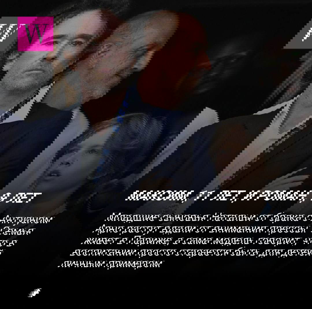 Взрослый мужчина и ребёнок стоят рядом на общественном мероприятии; на заднем плане размытые фигуры и сцена с официальным характером.